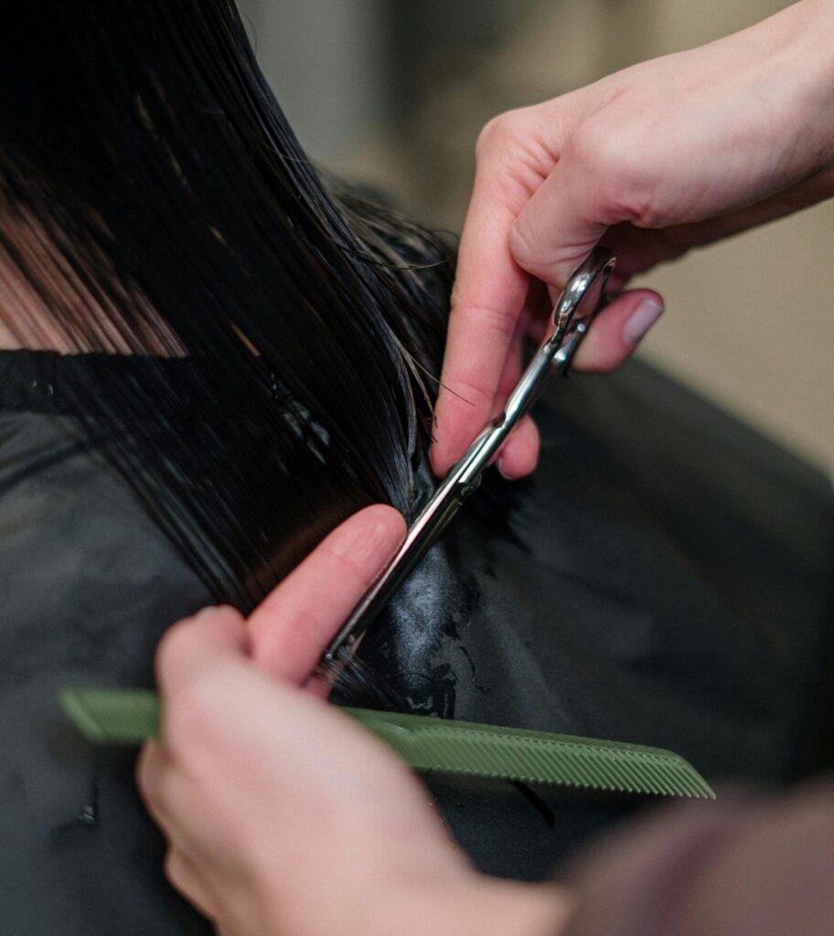 Close-up of a hairdresser cutting black hair in a salon, focusing on precision and style.