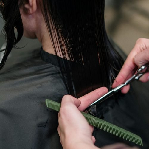 Close-up of a hairstylist cutting a woman's hair in a salon, showcasing precise techniques.